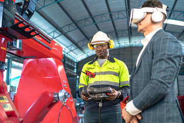 Business man and Factory engineer talking and shaking hands on business cooperation agreementAfrican American male engineer worker using tablet with the automatic robotic machine in the factory.