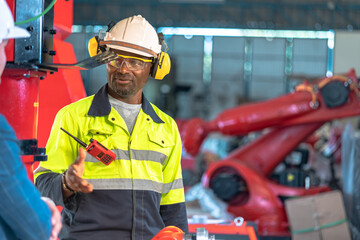 African American factory worker working with adept robotic arm in a workshop . Industry robot programming software for automated manufacturing technology .