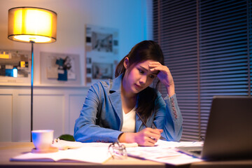 Entrepreneur using tablet pc while working from dark office working on deadline. Business asian woman working overtime at home.