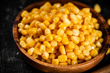 Canned corn on a wooden plate.