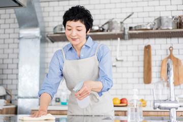 キッチンの作業台を掃除している日本人女性 - obrazy, fototapety, plakaty