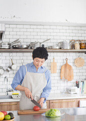 明るく清潔な広々としたキッチンで料理をするアジア人女性