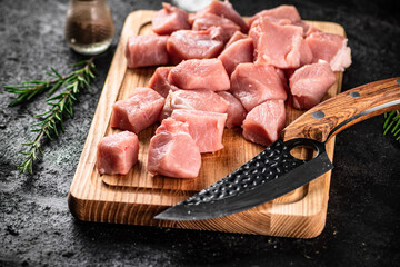 Chopped raw pork on a cutting board with knife, spices and rosemary. 