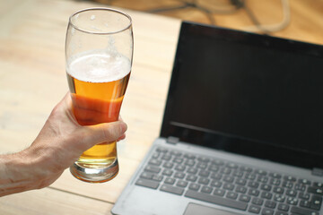 person holding a beer mug next to a laptop