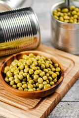 Canned green peas on a wooden cutting board. 