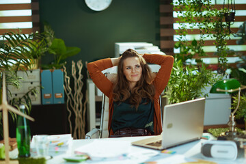 relaxed business owner woman in green office using laptop