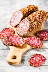 Cut into pieces of salami on a wooden cutting board. 