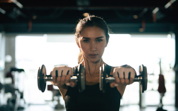 Young woman lifting dumbbells in the gym.