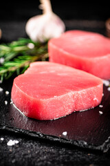 Raw tuna on a stone board with rosemary and garlic. 