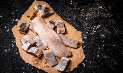 Pieces of salted herring on paper with salt. 