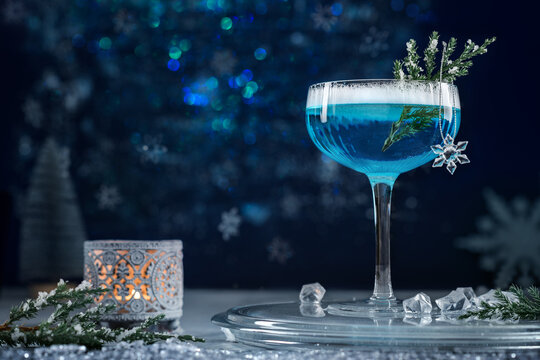 Alcoholic cocktail with gin decorated with a snowflake on a blue background. Cocktail Blue Lagoon. A blue alcohol drink.