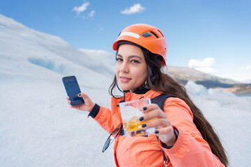 La joven está sobre el glaciar Perito Moreno en Argentina celebrando su caminata  y disfrutando un vaso de whisky.
 - obrazy, fototapety, plakaty