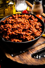 Bolognese sauce on a cutting board with cherry tomatoes and dry pasta. 