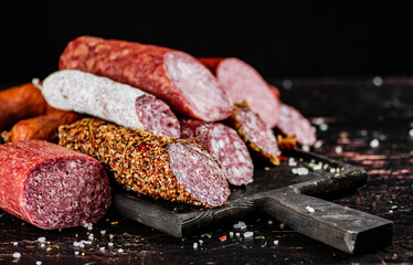 Different types of salami sausage on a cutting board. 