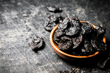 Prunes in a wooden plate on the table. 