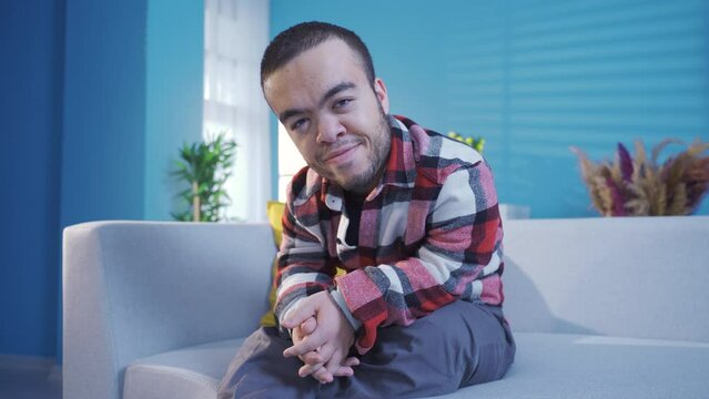 Dwarf young man at home looking at camera happily and resolutely, confident and brave.
Close-up portrait of happy and confident disabled young man with dwarfism.
