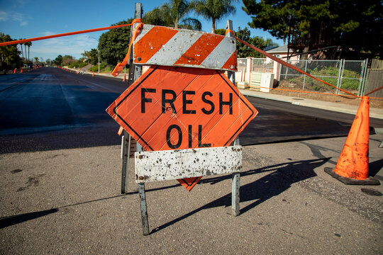 Traffic sign stating Fresh Oil with asphalt slurried road in the background