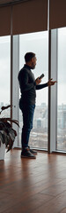 Adult man standing near big window in office space