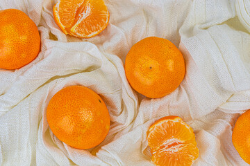 Fresh tangerines are located on a white cloth background