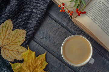 Colorful autumn maple leaves, book and cup of coffee on wooden texture, top view.