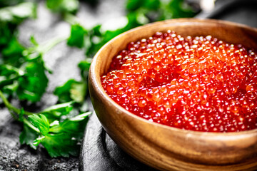 Red caviar in a plate on a cutting board with parsley. 