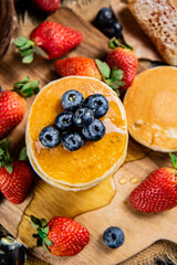 A bunch of pancakes with berries and honey. 