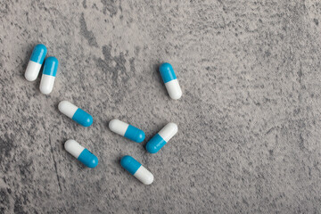 Blue and white pill capsule on gray background, selective focus, copy space.