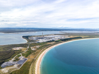 High angle aerial drone view of Tiwai Point peninsula at the entrance to Bluff Harbour on the southern coast of the South Island of New Zealand. It is known for a large industrial aluminium smelter.