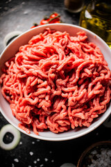 Minced meat in a bowl with onion rings, tomatoes and spices. 