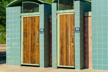 Public restroom that is unisex for both men and women to use with green or blue tiles on exterior with wooden door