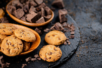Cookies with pieces of milk chocolate on a stone board. 