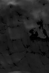 Black and white photo of the texture of the surface of the movement of water waves on a gray bottom. The background is dark.
