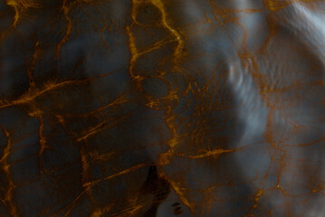 Abstract photo of the reflection of light from the surface of the movement of the waves of the transparent water of the river from the sky in gray-orange tones.
