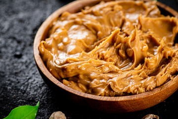 Peanut butter in a wooden plate on the table. 