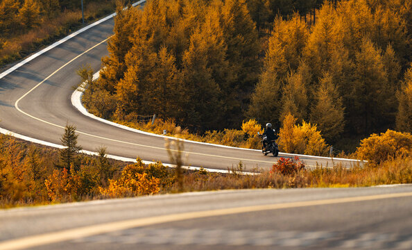 Young woman riding a motorcycle in the autumn suburbs