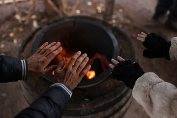 Man and woman warm their hands over fire.