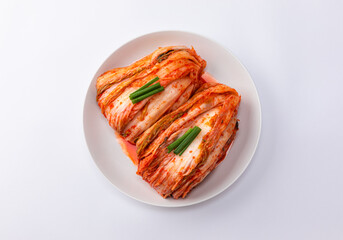 Korean kimchi. Korean traditional cabbage kimchi on a white plate viewed from above. White background, closeup.