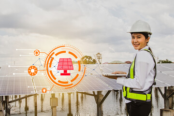 Professional asian female electrical engineer in hard hat works in the field checking solar panel...