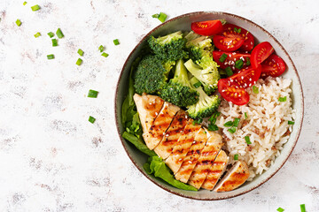 Delicious buddha bowl with grilled chicken, fresh vegetables and rice on a light background. Top view, above