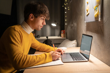 College student studying at night in dormitory using laptop computer.