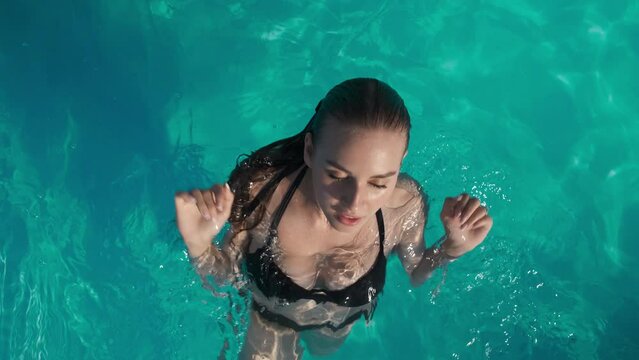 Top view of sexy girl in swimsuit swimming and posing in outdoor swimming pool