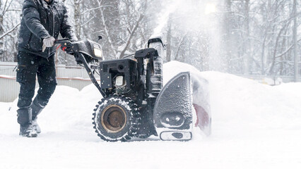 a janitor on a snowplow removes snow in the courtyard of a residential building