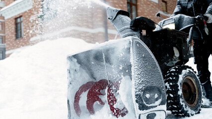 a janitor on a snowplow removes snow in the courtyard of a residential building