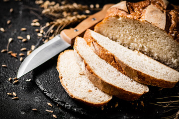Sliced on a stone board wheat bread with grains. 