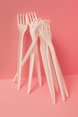 White plastic forks on pink background. Close-up.
