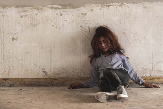 depression sad alone woman sit in dirty abandon building after raped violence against by bandit. Raped girl sit and cry in scared depressed emotion.