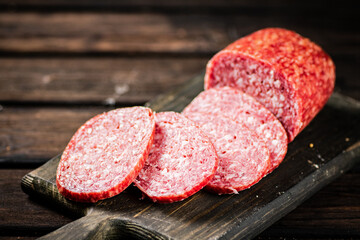 Pieces of salami sausage on a cutting board. 
