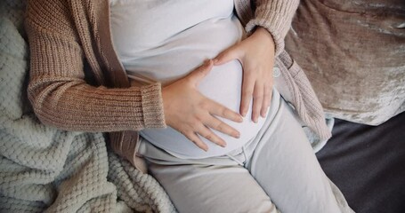 Close up pregnant woman making heart shape with her hands on her belly