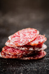 Sliced delicious salami sausage. On a black background.