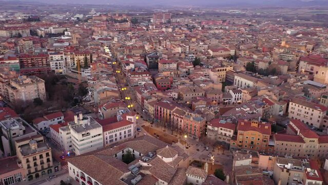 View from drone of Spanish town of Vic with tiled roofs of old buildings and ancient cathedral in winter evening, Barcelona province, Catalonia